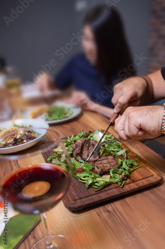 man in the cafe eats beef steak with greens close-up