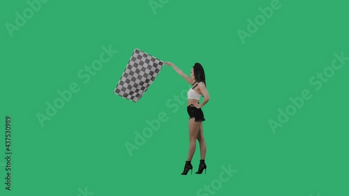 Side view of brunette waving black and white checkered racing flag to signal start of competition. Young woman posing full length against background of green screen. Slow motion ready, 4K at 59.94fps. photo