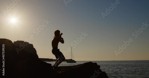 Ragazzo gioca a boxe in spiaggia su uno scoglio photo
