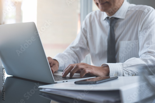 Businessman working on laptop computer with business document on table in modern office