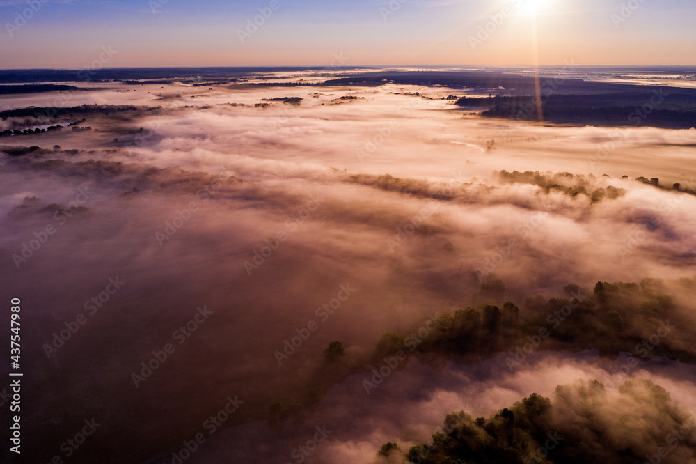 Aerial  view of a beautiful summer  landscape with a fog while dawn.  Photo from drone of a foggy landscape in spring. Top view to land while sunrise. Early morning in nature, misty  weather.