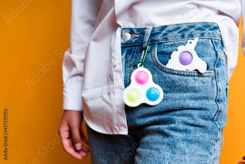 Photo of a children's toy of a simple dimple keychain hanging on a girl's jeans. Antistress toys
