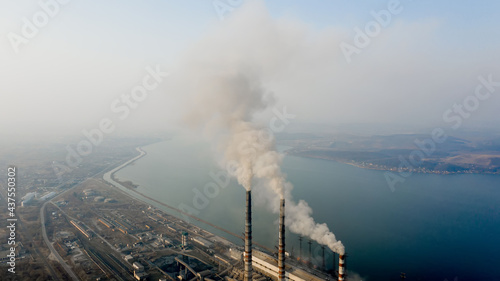 Aerial view of high chimney pipes with grey smoke from coal power plant