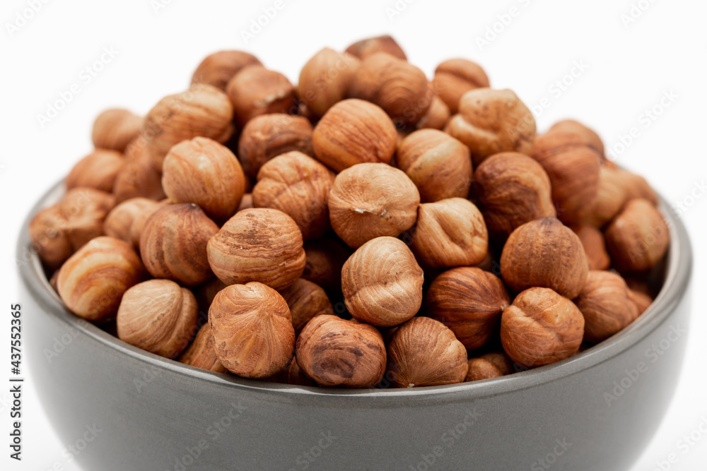 Close-up of peeled hazelnuts in a bowl isolated on white, side view. Template for designers Close-up of peeled hazelnuts in a bowl isolated on white, side view. Template for designers