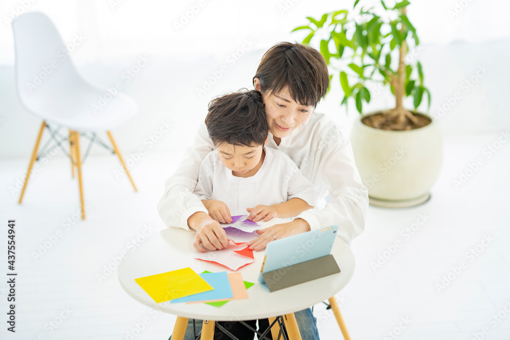 タブレットPCを見ながら折り紙をする親子