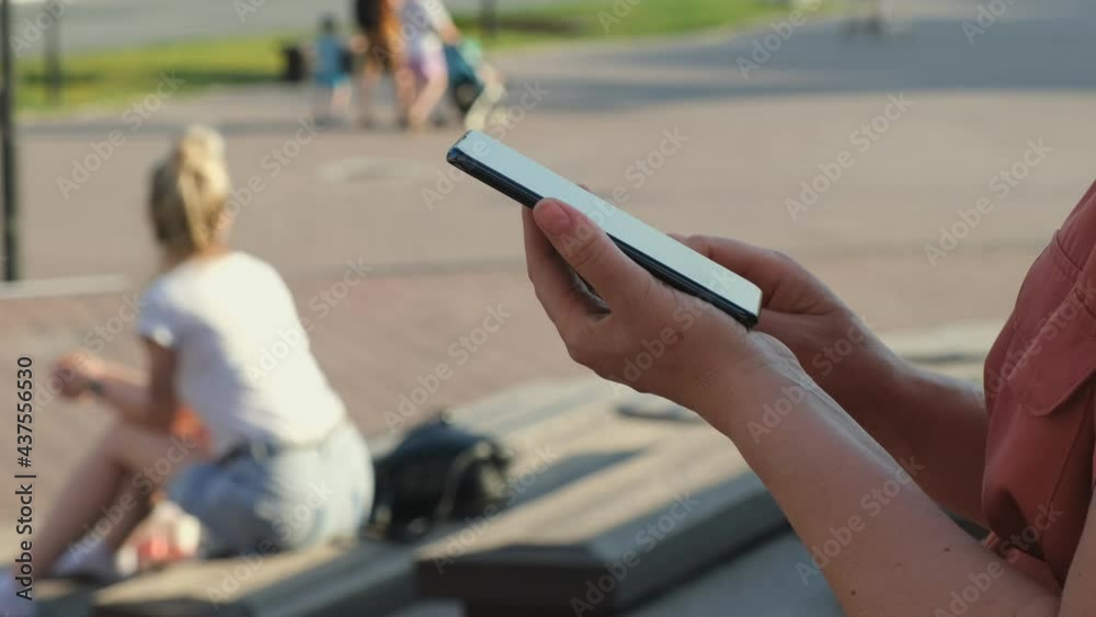 4k Smiling businesswoman at street sitting on a bench reading phone message or downloading an app for his mobile phone.