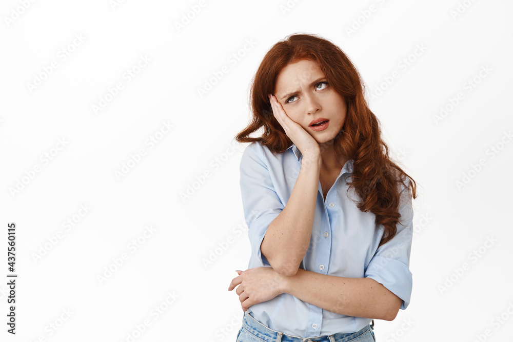 Bored and annoyed reluctant redhead student roll eyes, lean on hand and standing indifferent, attend boring meeting, standing bothered against white background Bored and annoyed reluctant redhead student roll eyes, lean on hand and standing indifferent, attend boring meeting, standing bothered against white background