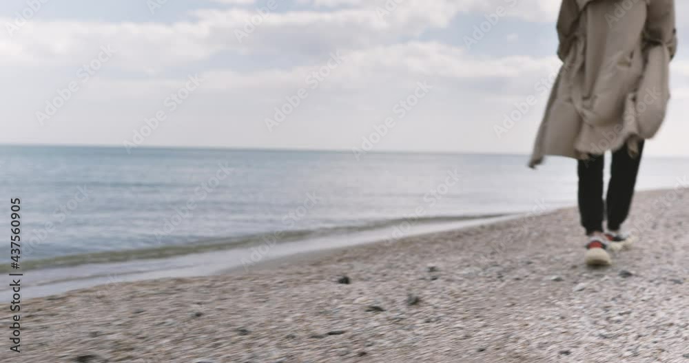 Tourist traveler woman walking along in sneakers on beach coastline leaving footprints in sand. Female feet legs on ocean sea. Sea waves. Tourist traveler woman walking along in sneakers on beach coastline leaving footprints in sand. Female feet legs on ocean sea. Sea waves.