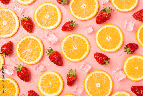 Top view photo of strawberries orange slices ice cubes and water drops on isolated pastel pink background