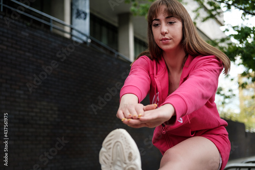 Young woman stretching in front of a building.