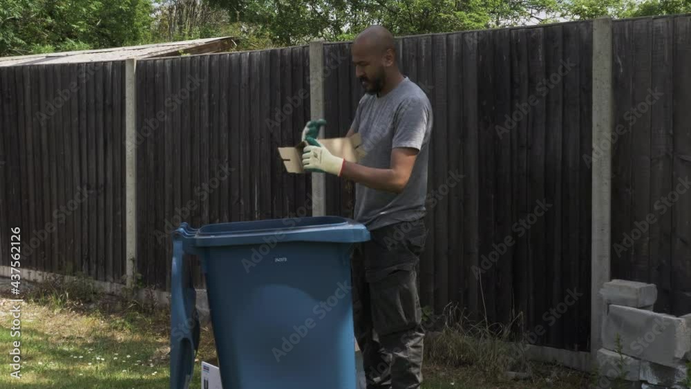 Adult UK Asian Male Sorting And Ripping Cardboard Beside Blue Recycling ...