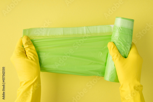 Above photo of garbage bag and yellow gloves isolated on the yellow background © ActionGP