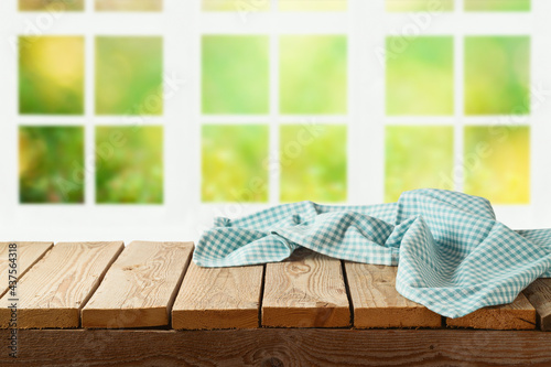 Empty wooden table with tablecloth over window garden background. Summer mock up for design and product display.