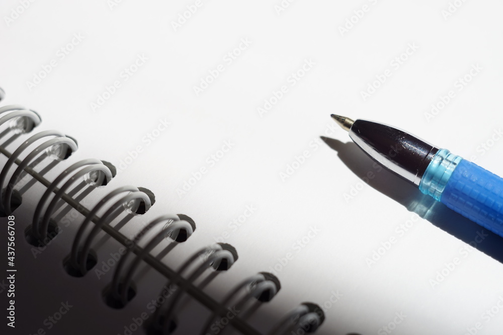 Blue ball pen on a bright sunny white notebook paper Blue ball pen on a bright sunny white notebook paper