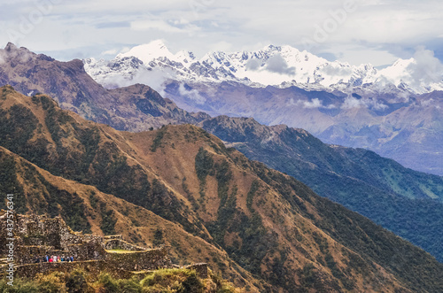 Distant view of Phuyupatamarca ruins with unrecognizable people on it and the huge valley landscape behind. Inca trail to Machu Picchu from the Inca's ancient civilization in Peru. South America