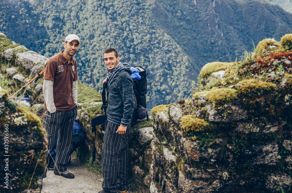 Two backpackers male friends smiling at camera on Phuyupatamarca ruins. Inca trail to Machu Picchu archaeological site from the Inca's ancient civilization in Peru. South America