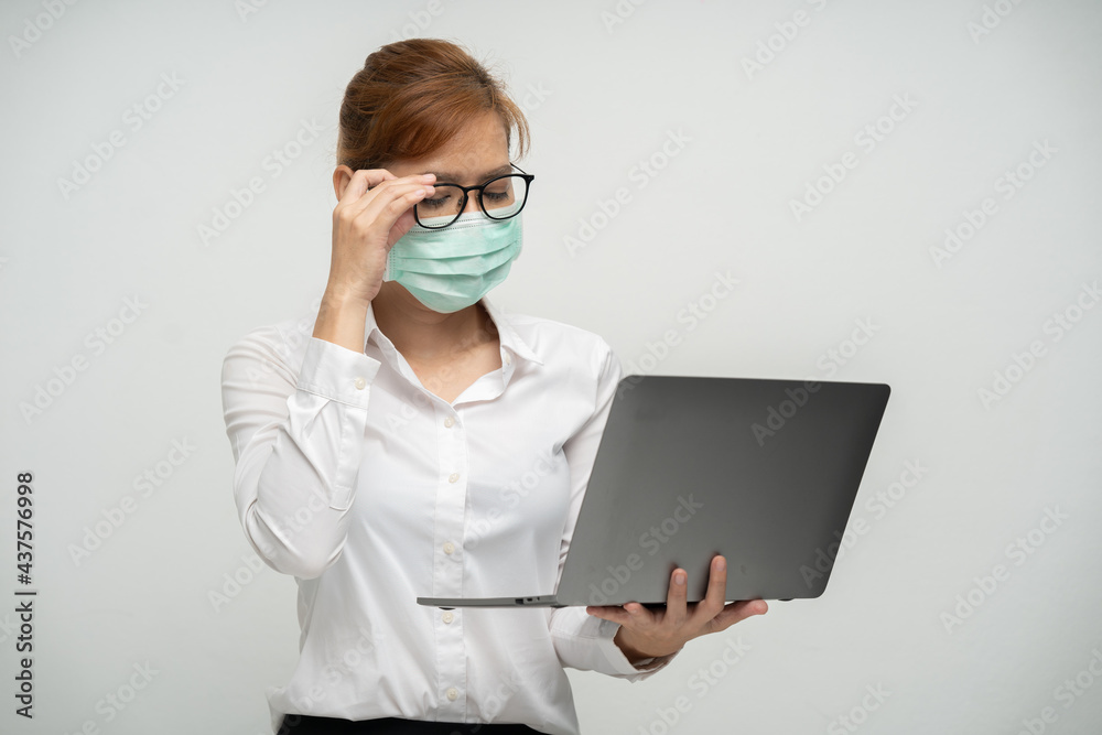 Pretty office worker wearing a mask using a laptop to work. Pretty office worker wearing a mask using a laptop to work.