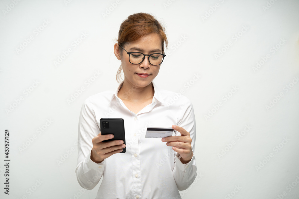 A beautiful office woman wearing a white shirt is using a smartphone and credit card to pay for products.Online shopping.