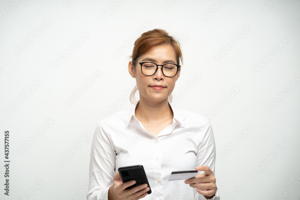 A beautiful office woman wearing a white shirt is using a smartphone and credit card to pay for products.Online shopping. A beautiful office woman wearing a white shirt is using a smartphone and credit card to pay for products.Online shopping.