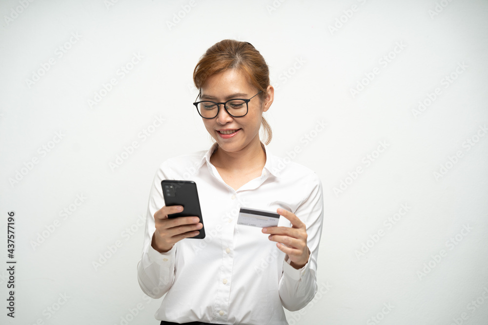 Fototapeta premium A beautiful office woman wearing a white shirt is using a smartphone and credit card to pay for products.Online shopping.