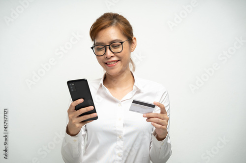 Pretty office worker wearing a mask using a mobile phone and credit card to pay for online shopping