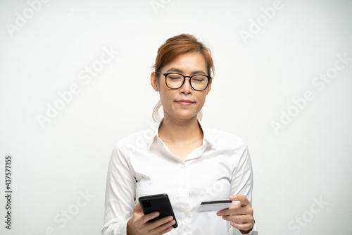 A beautiful office woman wearing a white shirt is using a smartphone and credit card to pay for products.Online shopping.