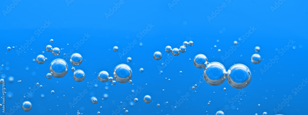 Oxygen bubbles float up in the liquid. Air bubbles under water. Clear blue water background. Sparkling water. Carbon dioxide