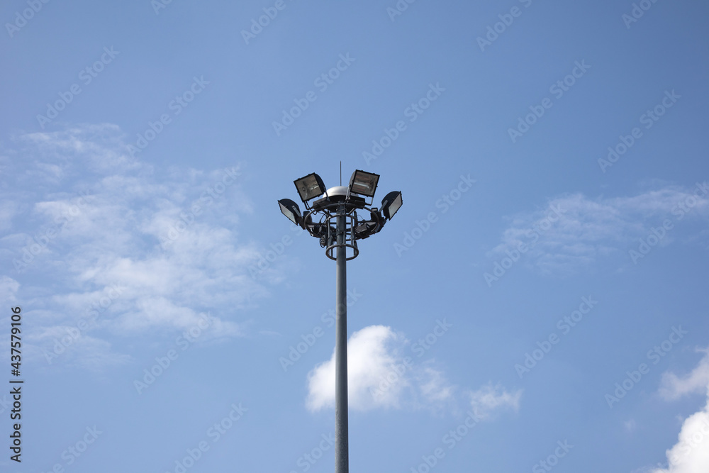 Spotlight on an aluminum pole with a background in the blue sky.