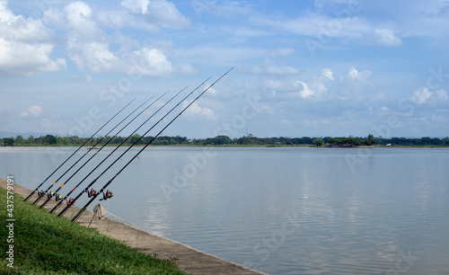 Fishing rod by the river with blue sky, Beautiful scenery. holiday activities concept