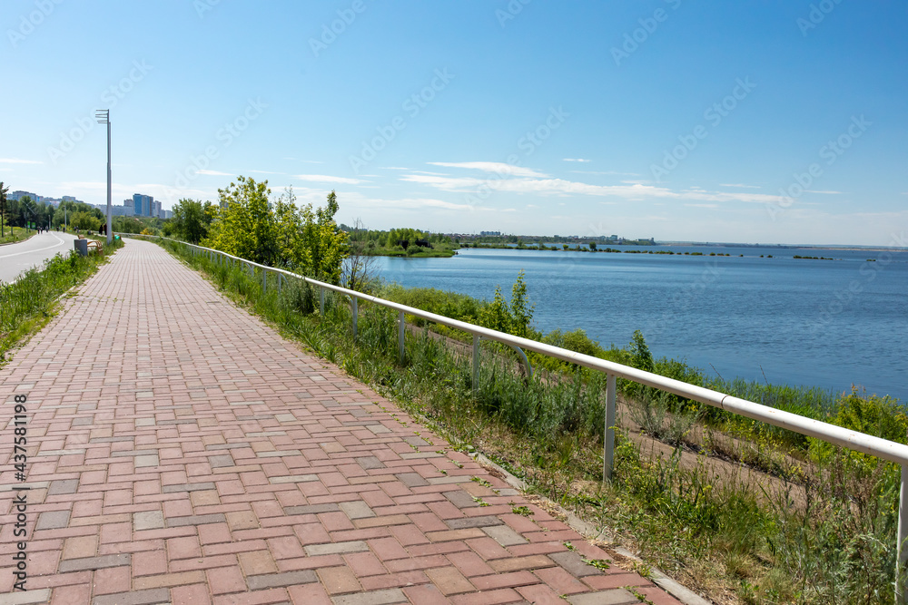 Embankment of the Kama River in Naberezhnye Chelny, Tatarstan, Russia. The shore is reinforced with concrete slabs, the pedestrian path is paved with paving  stones.