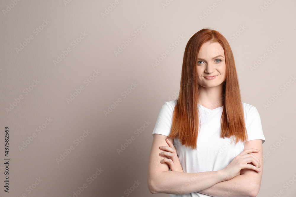 Candid portrait of happy young woman with charming smile and gorgeous red hair on beige background, space for text Candid portrait of happy young woman with charming smile and gorgeous red hair on beige background, space for text