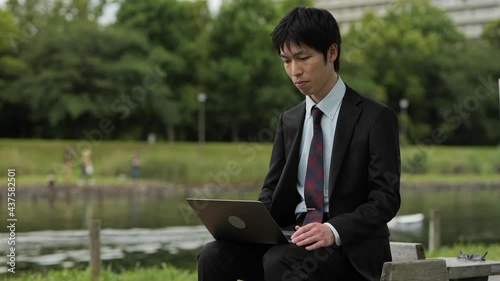 コロナ禍に川原でビジネスパーソンがパソコンを使ってオンライン会議、挨拶1