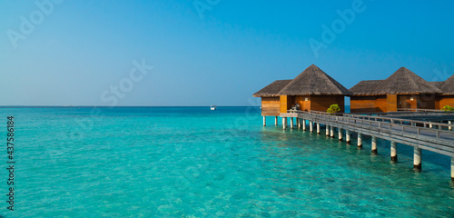 Amazing wide panorama of tropical Maldives island on a sunny day. Exotic vivid beach background with blue turquoise lagoon and palm trees. Luxurious holiday and romantic honeymoon destination. © SeaRain