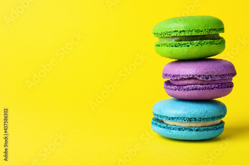 Delicious colorful macarons on yellow background  closeup  Space for text