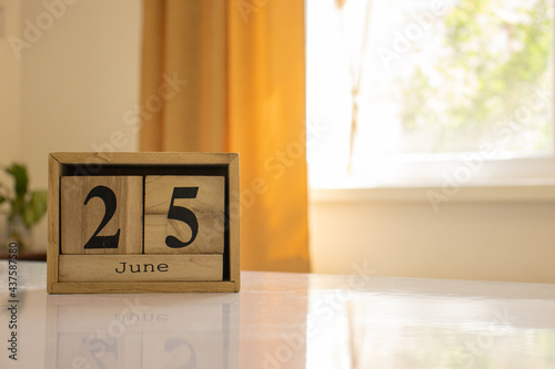 Canvas-taulu Wooden blocks of the calendar represents the date 25 and the month of June on the background of a window, curtain and a plant