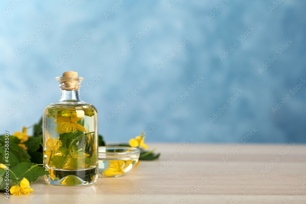 Bottle of celandine tincture and plant on white wooden table, space for text Bottle of celandine tincture and plant on white wooden table, space for text