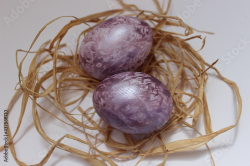 2 marble Easter eggs in a nest in purple color. Easter background.
