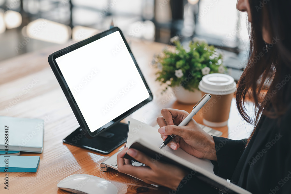 Side view of a businesswoman holding a pen to take notes using tablet blank white screen . Mock up. Side view of a businesswoman holding a pen to take notes using tablet blank white screen . Mock up.