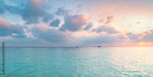 Amazing wide panorama of tropical Maldives island. Exotic beach background with blue lagoon, turquoise water and palm trees during beautiful sunrise. 