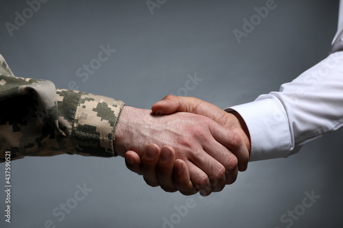 Soldier and businessman shaking hands against grey background, closeup Fototapet