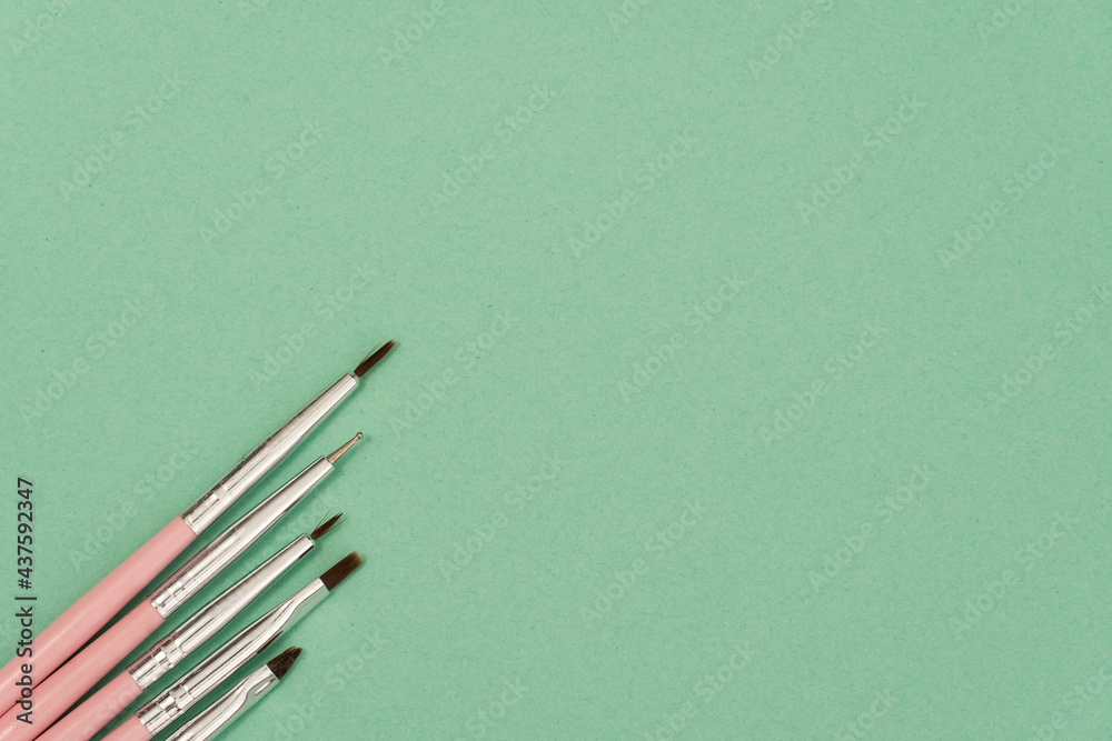 cosmetic flat lay: pink makeup brushes on green background cosmetic flat lay: pink makeup brushes on green background