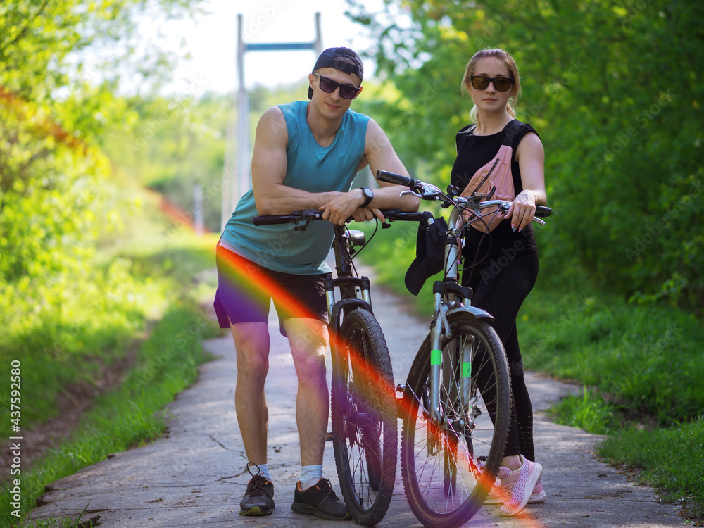 Obraz premium Young couple man and woman on a summer bike ride in the park