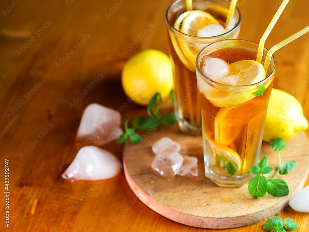 Two glasses of cold summer tea with lemon and mint on the wooden table. Refreshing ice drink Two glasses of cold summer tea with lemon and mint on the wooden table. Refreshing ice drink