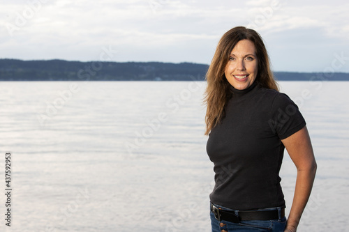 Portrait of beautiful 50 year old woman standing in front of the Puget Sound ocean water in Washington State