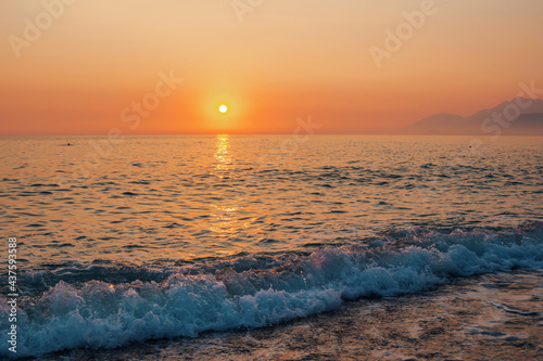 Beautiful landscape - beach on sunset    red and orange sky and sunlight reflecting on sea water.
