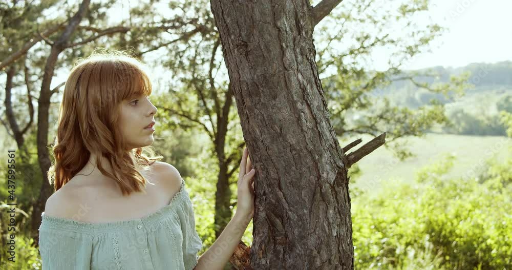 Attractive European chestnut teen girl with natural makeup has a pleasure of nature near a tree in forest on a sunny day Attractive European chestnut teen girl with natural makeup has a pleasure of nature near a tree in forest on a sunny day