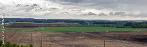 Panorama of freshly plowed agricultural fields under a cloudy sky. Detailed natural landscape with fields and forests of Belarus © Ilya