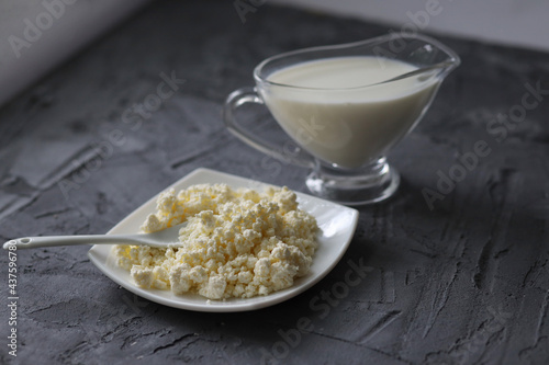 An assortment of dairy products on a wooden table in the morning for breakfast - milk, cheese, egg, yogurt, sour cream, cottage cheese and butter.