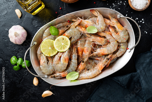 Fresh raw shrimp marinated with spices and lime juice, ready to roast. Black background. Top view