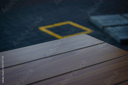 Wooden table against a background of tiles and bright yellow squares on the tiles. Blurred background. 